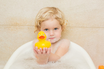 smiling child bathing in the bathroom with foam