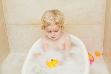 smiling child bathing in the bathroom with foam