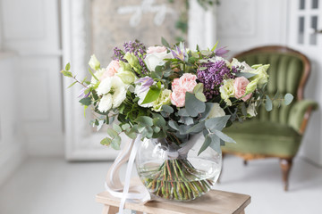 Sunny spring morning in living room. Beautiful luxury bouquet of mixed flowers in glass vase. the work of the proffesional florist at a flower shop.