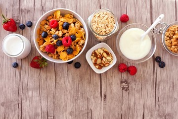 Cereal and ingredients for a healthy breakfast forming a top border over a wood background. Top view. Copy space.