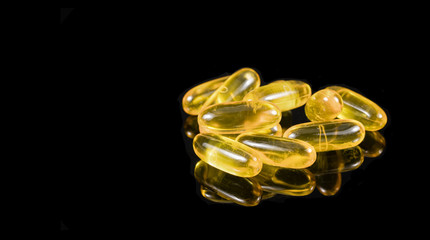 Pills of fish oil on a black background