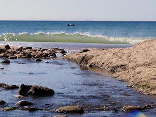 Fototapeta premium Río desembocando en el mar. Olas en el mar. Océano. Cielo azul. Playa. Arena.