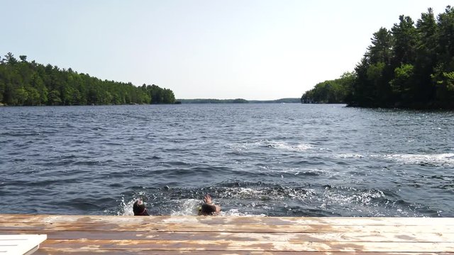 boy and girl jump into lake together holding hands 4k