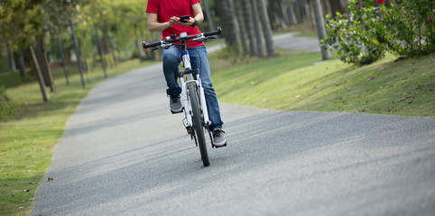Obraz premium cyclist use cellphone while riding bike in tropical park