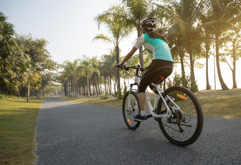 one woman cyclist riding bike in tropical spring park