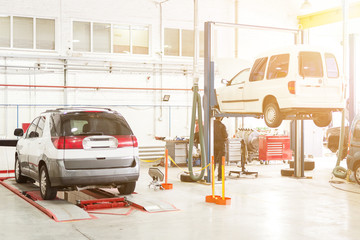 Car service center. Vehicle raised on lift at maintenance station. Auomobile repair and check up
