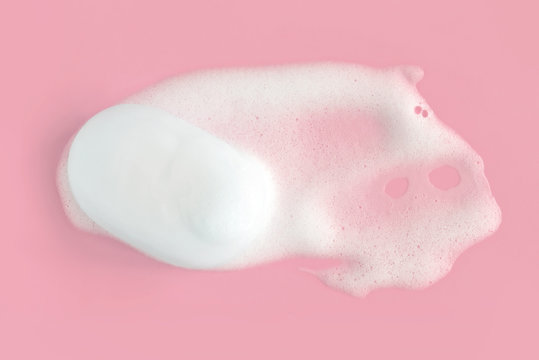 Soap foam bubbles on pink background macro close up.