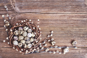 Easter willow wreath and  quail Easter eggs on old wooden background. Top view, copy space