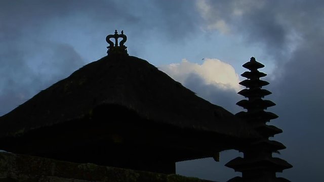 A Balinese temple stands in silhouette.