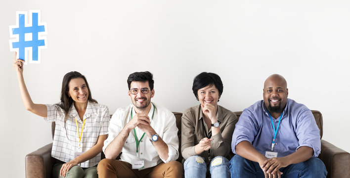 Diverse workers sitting together woman holding hashtag icon