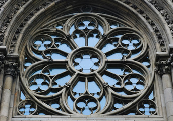 Round window with stained glass on facade of the building. Baroque and Gothic architecture. 