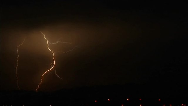 Lightening strikes illuminate a hillside.