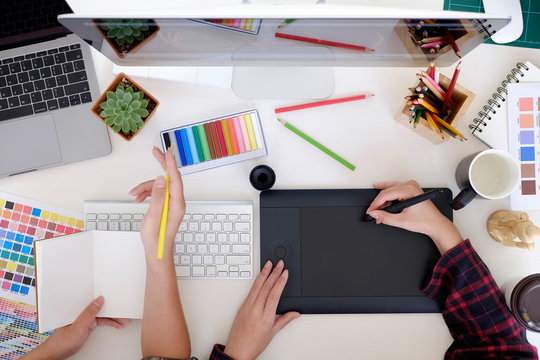 Graphic designer using digital tablet and computer - Powered by Adobe