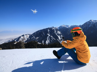 remote controlling a flying drone on winter mountain top