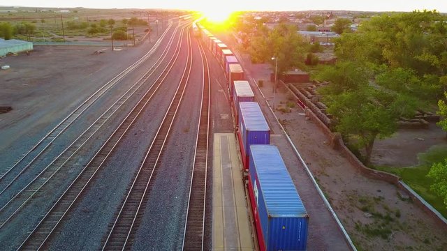 High aerial over a freight train full of containers for export heading into the sunset.