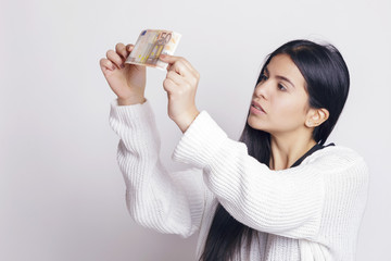 Latin woman checking a fifty euro banknote. Indoors, over a white background.