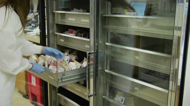 A nurse removes a bag of blood from a drawer at a blood bank.