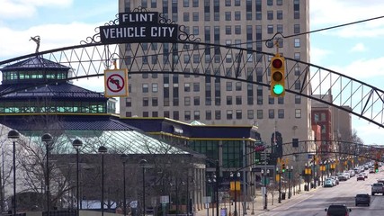 Establishing shot of Flint, Michigan main street and arch saying Vehicle City.