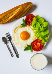 Breakfast with bread, fried eggs, milk and vegetables and fried tomato pieces isolated on white background