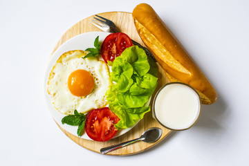 Breakfast with bread, fried eggs, milk and vegetables and fried tomato pieces isolated on white background