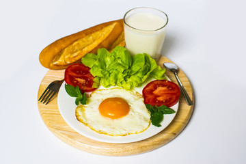 Breakfast with bread, fried eggs, milk and vegetables and fried tomato pieces isolated on white background