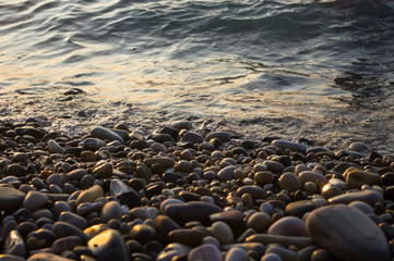 pebble stones on the sea beach, the rolling waves of the sea with foam