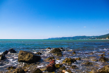 Fototapeta na wymiar rocky sea shore with pebble beach, waves with foam