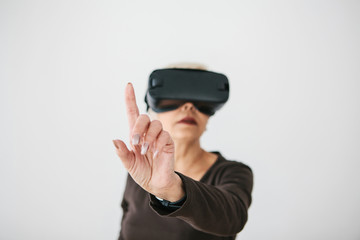 An elderly woman in virtual reality glasses. An elderly person using modern technology.