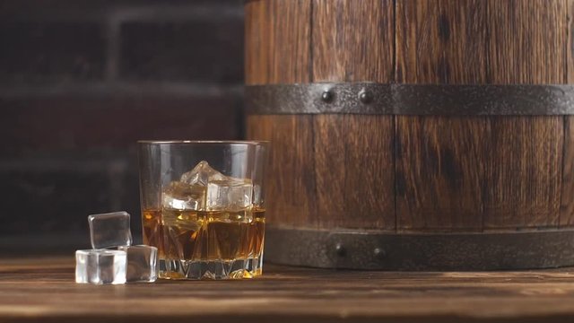 Glass of whiskey and wooden barrel in cozy cellar