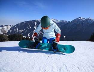 One young woman snowboarder ready for snowboarding on winter mountain top