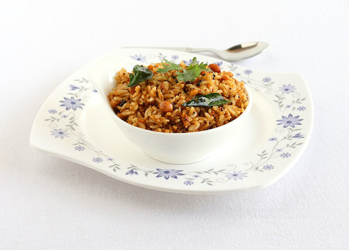 Puliyogare, south Indian traditional and popular vegetarian rice dish, in a bowl on a plate.