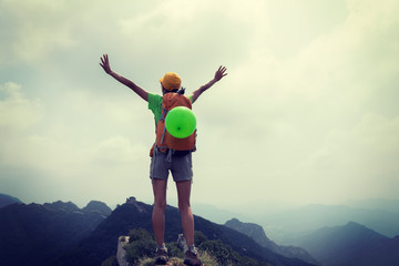 successful woman hiker open arms on the top of mountain