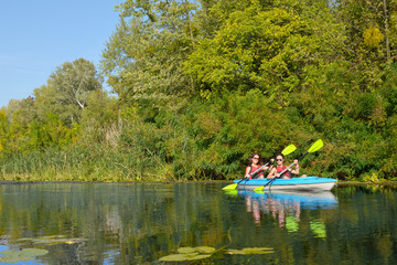 Family kayaking, mother and daughter paddling in kayak on river canoe tour having fun, active autumn weekend and vacation with children, fitness concept

