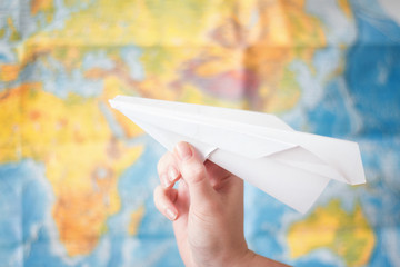 paper airplane in hand on world map background