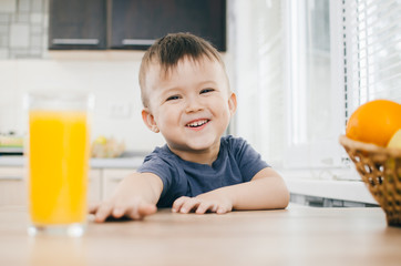 A charming little boy tries to reach the juice of orange