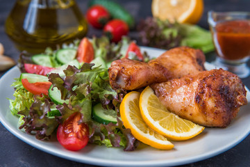 Fried chicken legs and fresh salad on a dark background
