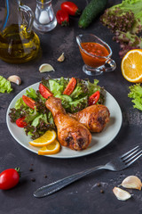 Fried chicken legs and fresh salad on a dark background