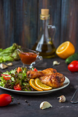 Fried chicken legs and fresh salad on a dark background