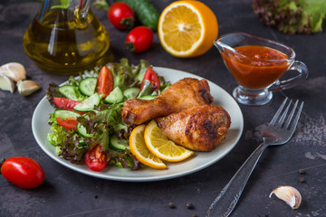 Fried chicken legs and fresh salad on a dark background