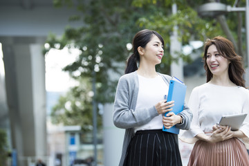 会話をしながらオフィス街を歩く女性社員達