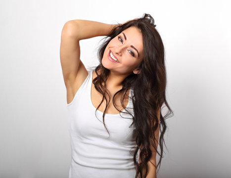 Beautiful positive fun happy woman in white shirt with toothy smile showing her epilation armpit on white background