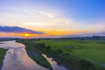 Fototapeta na wymiar 地平線に沈む夕日　多摩川河川敷夕景