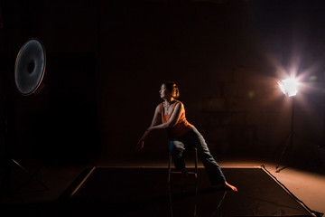 Woman in a yellow t-shirt in a dark Studio illuminated by colored spotlights