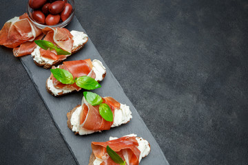 italian food with olives and prosciutto bruschettas on stone board