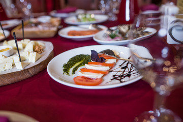 Caprese salad with mozzarella cheese, tomatoes and basil on plate. Banquet