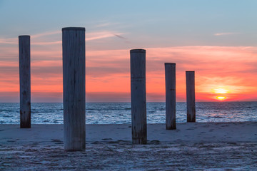 Wooden piles on an empty beach and a beautiful sunset sky over the sea, Petten, Holland,North Sea