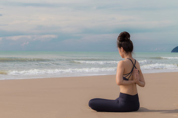 Fototapeta na wymiar Beautiful woman relaxing with yoga on the beach and practice lotus pose for meditation and warm up muscle in the morning,Feeling so comfortable and relax in holiday,Healthy Concept