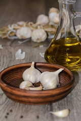 Garlic in a clay plate and olive oil on a wooden table