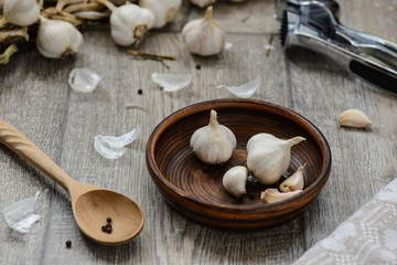 Fototapeta na wymiar garlic in a clay bowl with a wooden spoon and chop the garlic on a table