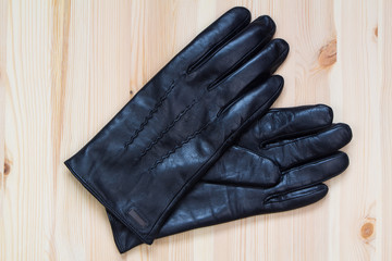 Black men's leather gloves on wooden background
